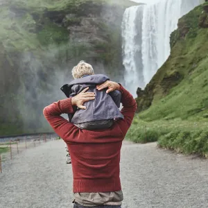 Iceland family holidays with friends and relatives: boy sitting on the shoulders of a male facing a waterfall.